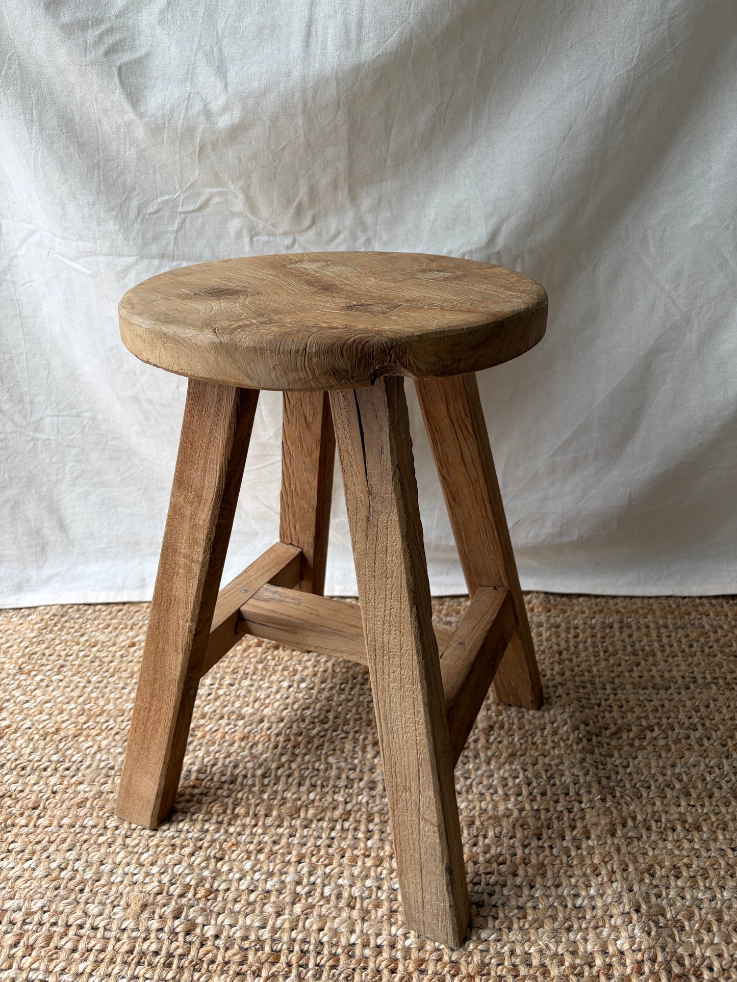 Vintage light wooden four legged stool with round top