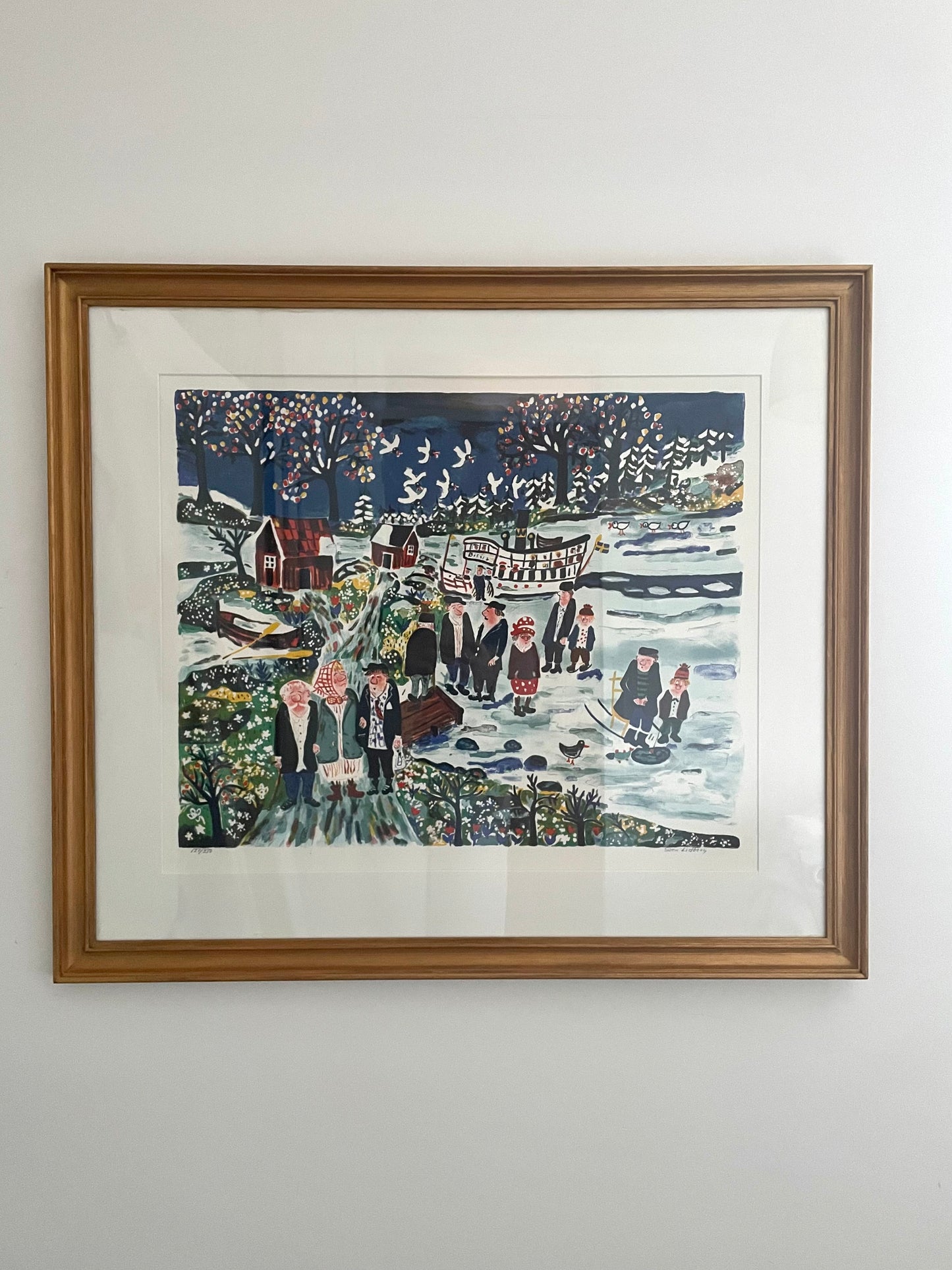 A colorful winter's day lithograph by Sven Lidberg, depicting a vibrant scene with people and snow, framed in a gold wooden frame.