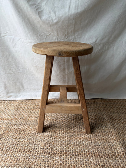 Vintage light wooden four legged stool with round top
