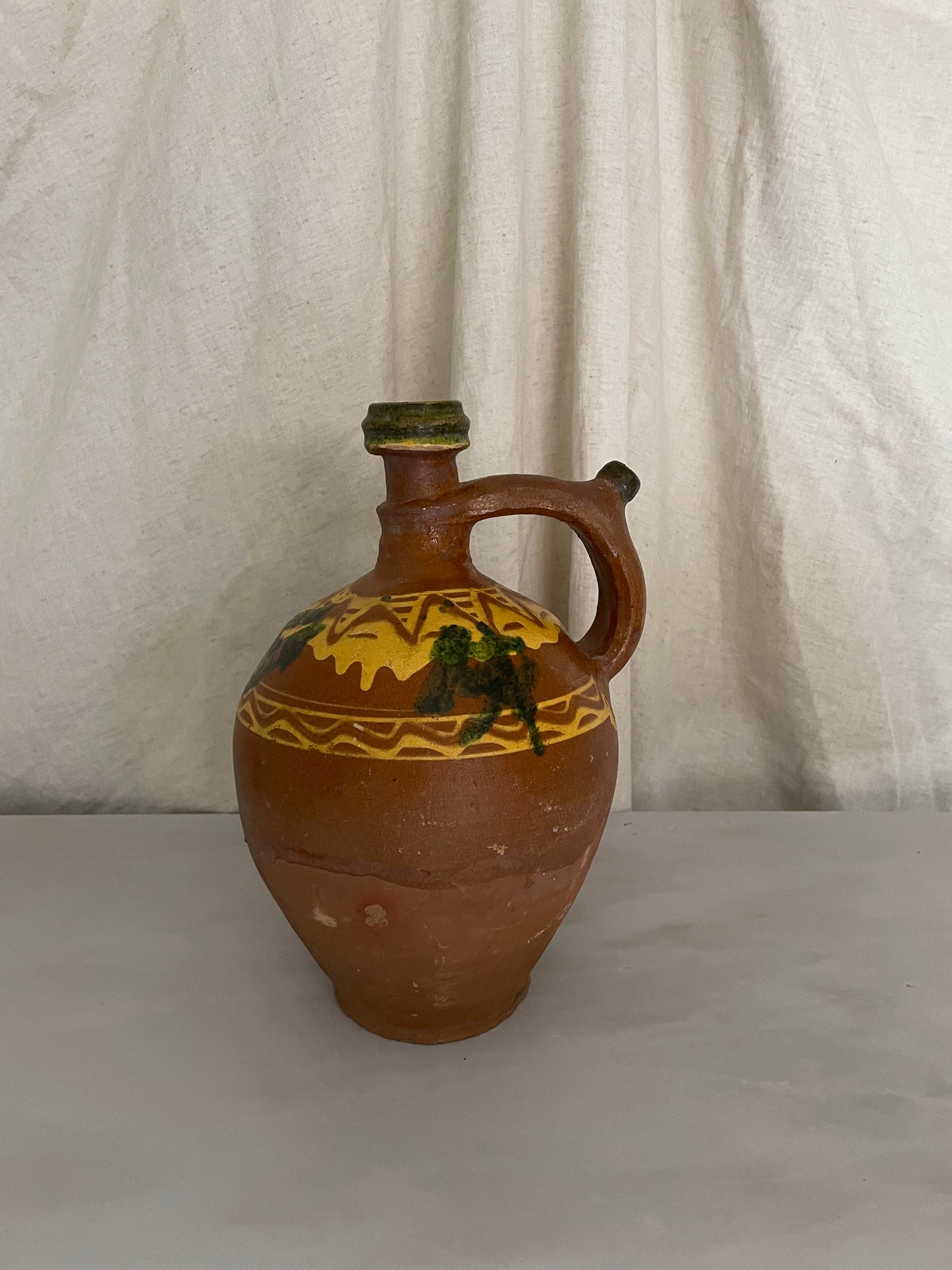 Terracotta jug with yellow and green