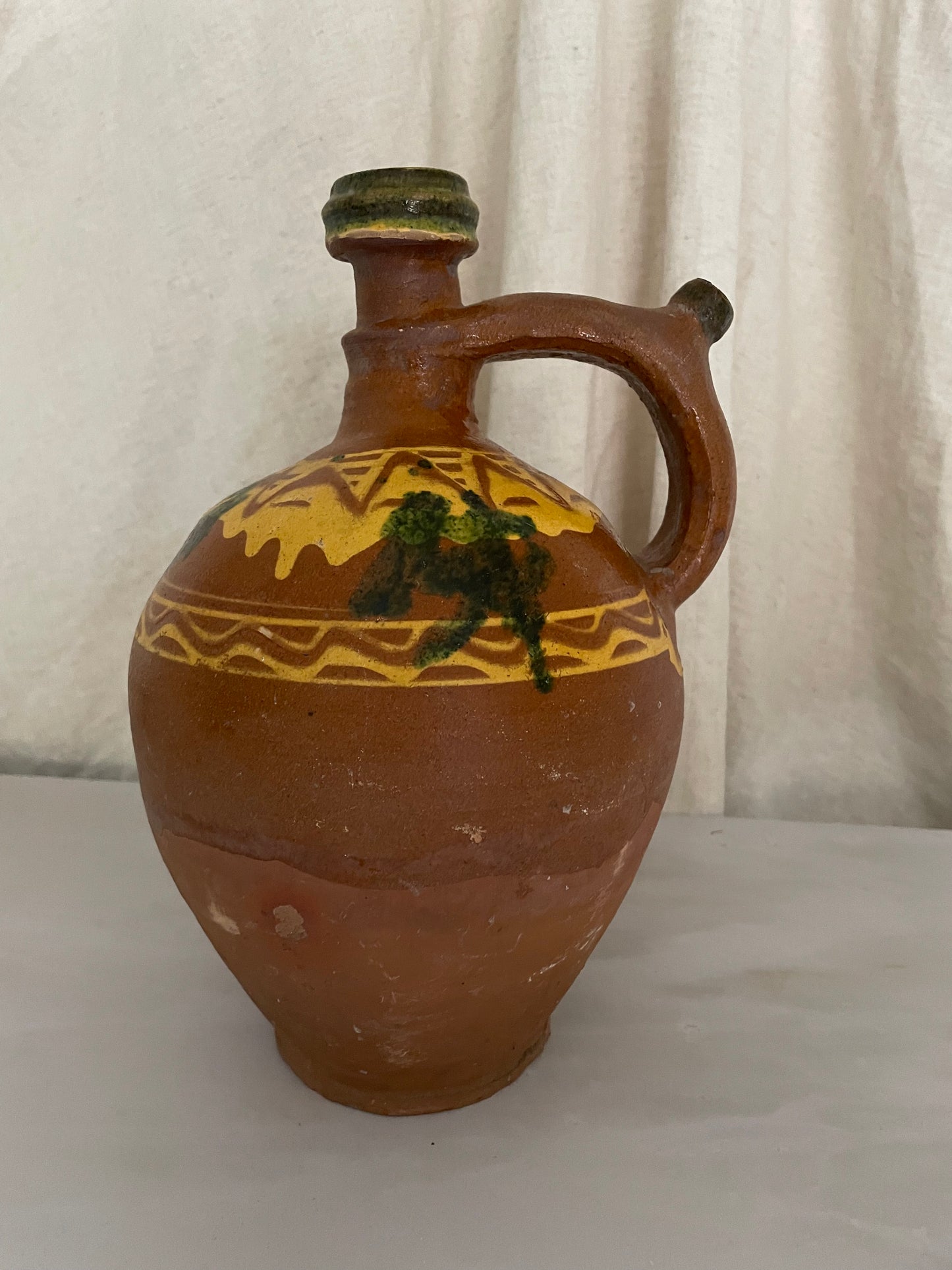 Terracotta jug with yellow and green