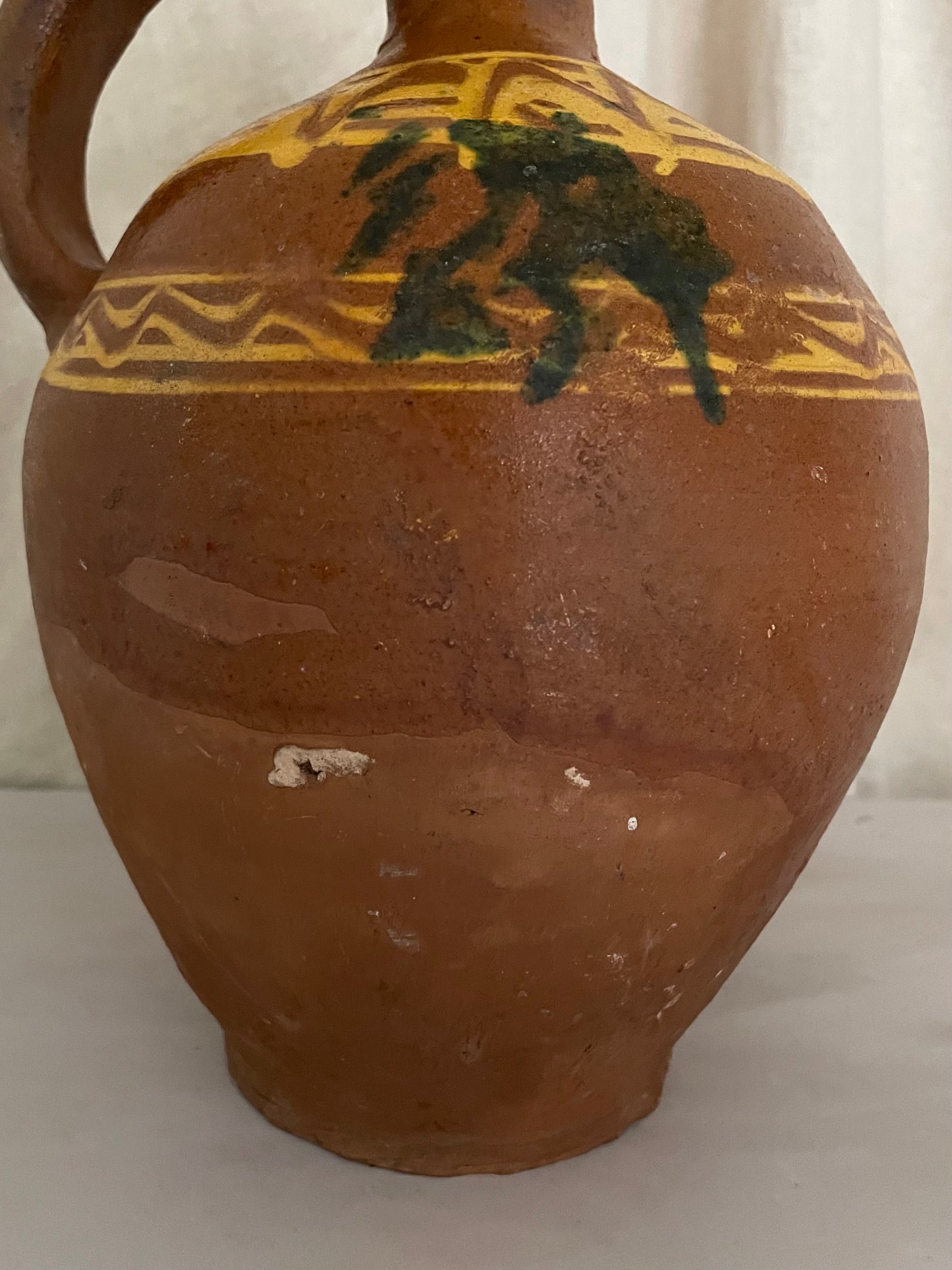 Terracotta jug with yellow and green